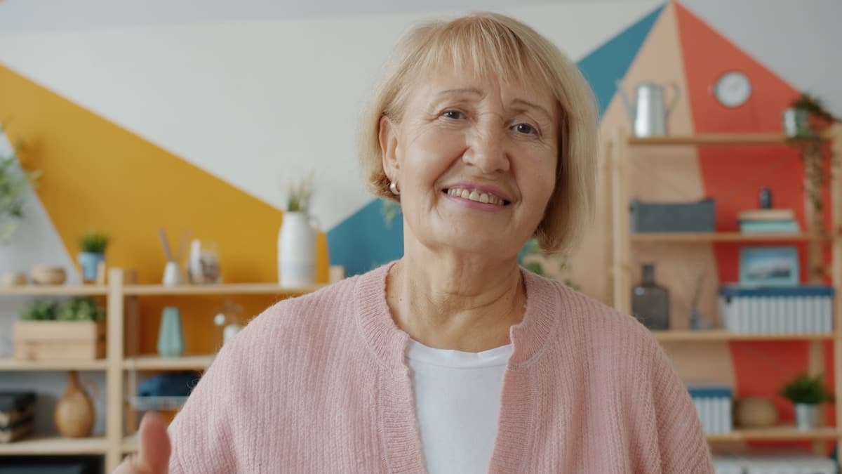 Smiling elderly woman in a pink cardigan indoors