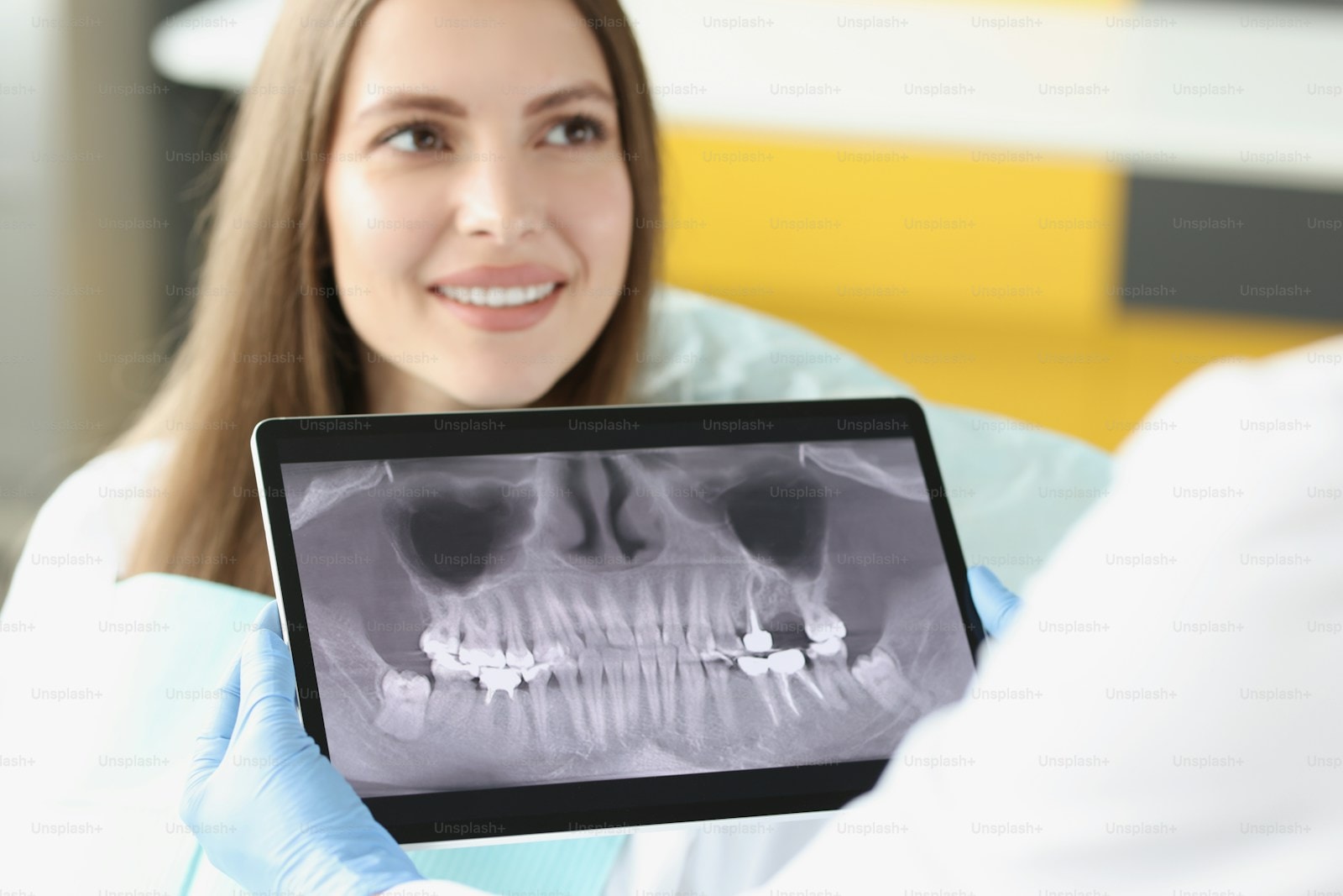 Dentist examining teeth X-ray on digital tablet during patient consultation — Emergency Dental Care at Hooper, Too Family Dentistry